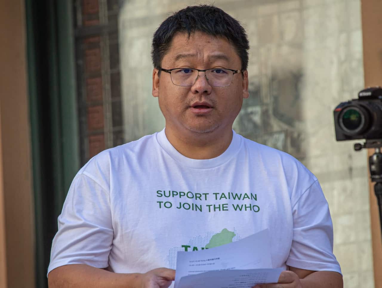 Man wearing glasses and a white t-shirt.