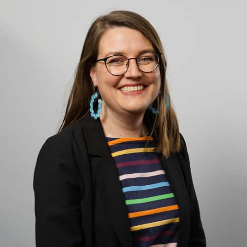 A woman wearing glasses and smiling.