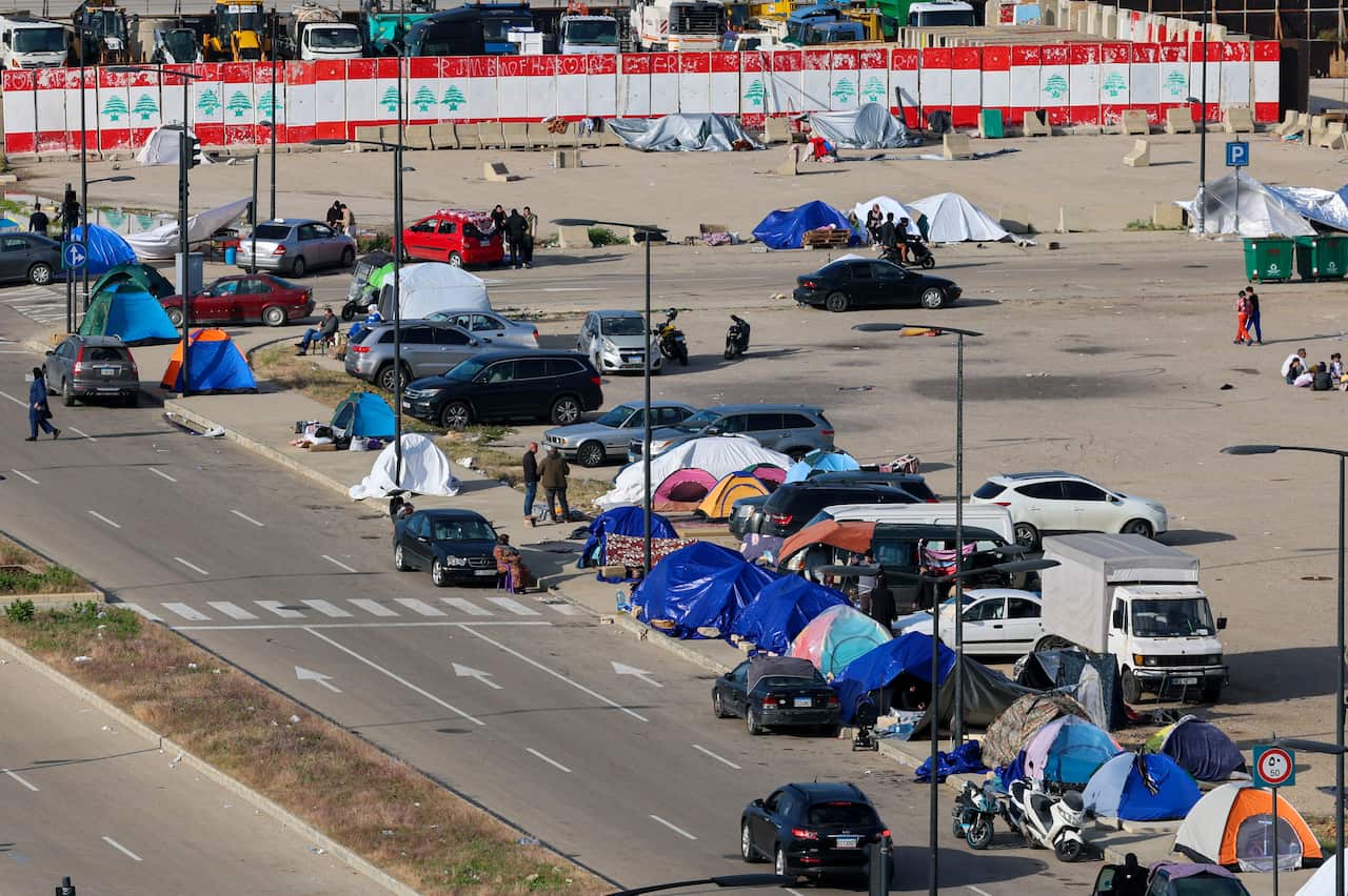 Rows of tents and parked cars along a road.