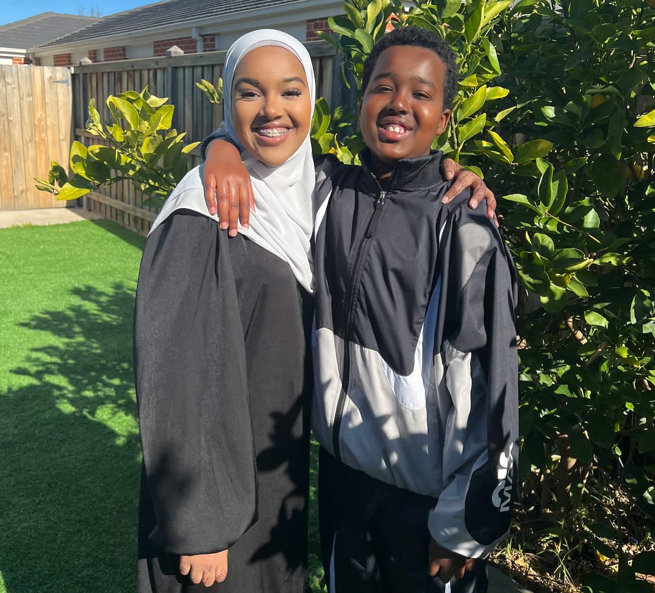 21-year-old Ikram and 16-year-old Hussein Ahmed posing for a photo in front of a garden bed.