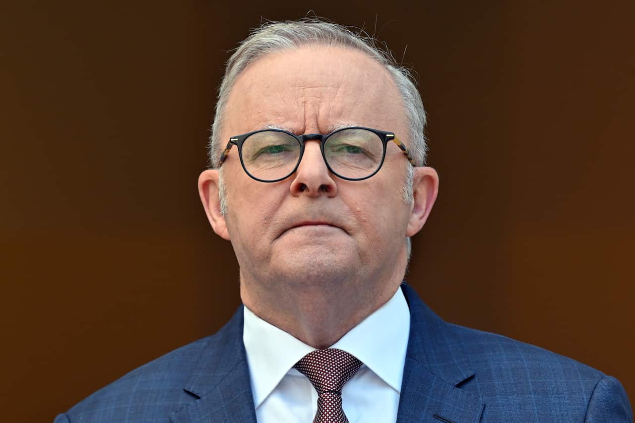 A man looks at the camera with a serious expression on his face.