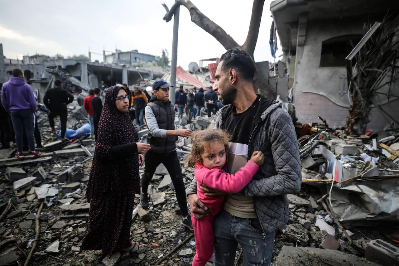 A man holds a child close while standing in the rubble of an Israeli airstrike in the Gaza Strip.