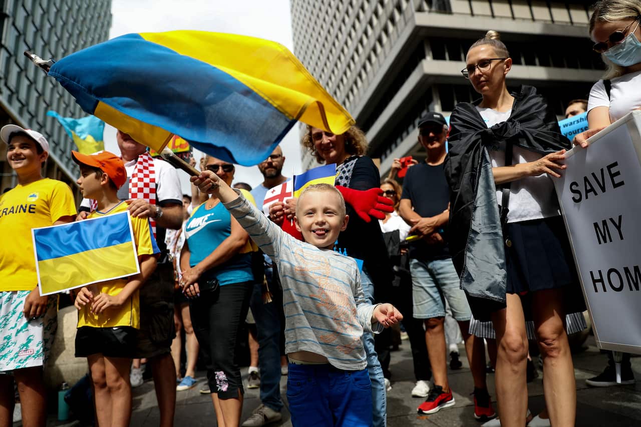 A child waves a Ukrainian flag as he stands among a group of people at a rally to support Ukraine in Sydney in February 2022.