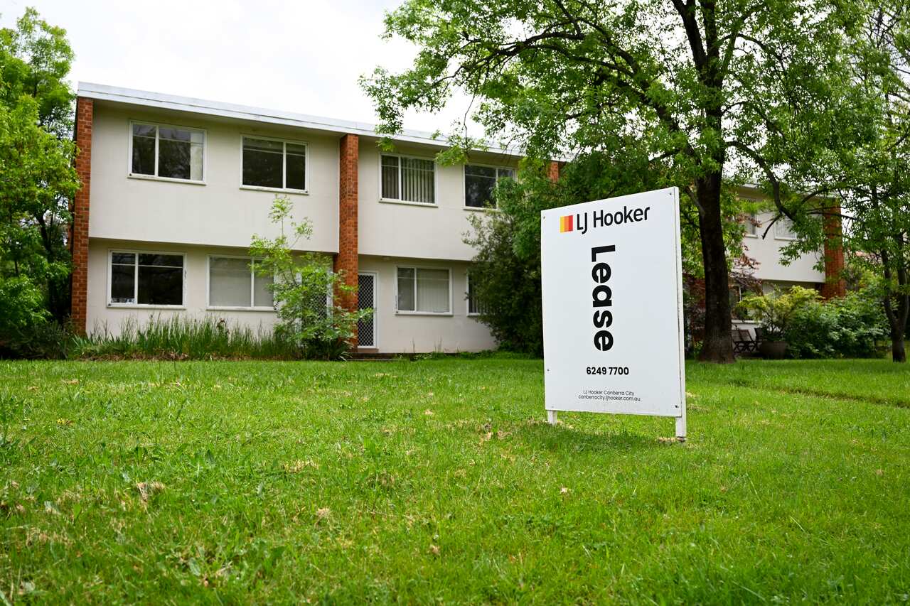 A two-storey apartment block with a 'Lease' sign on grass out the front