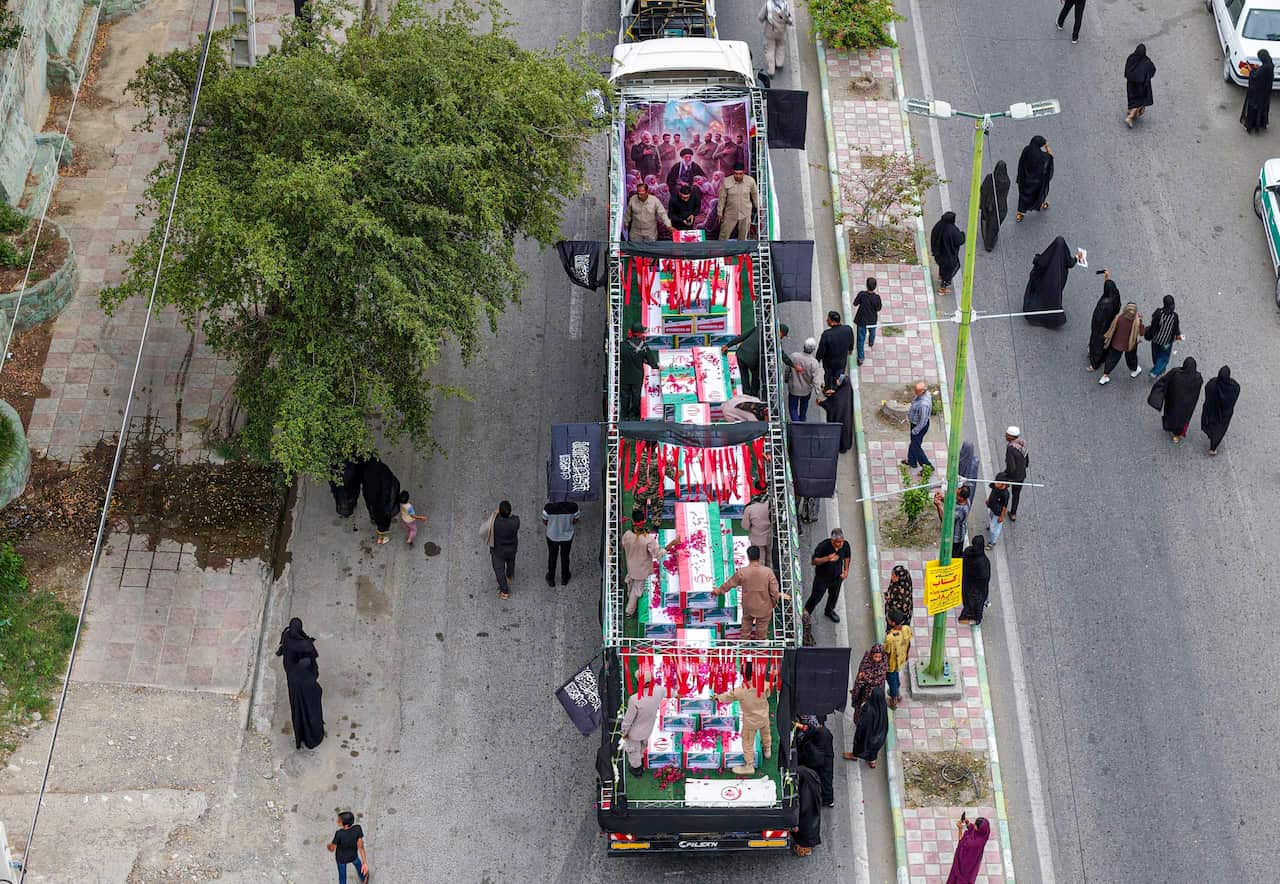 Aerial view of a truck carrying coffins draped in the Iranian flag