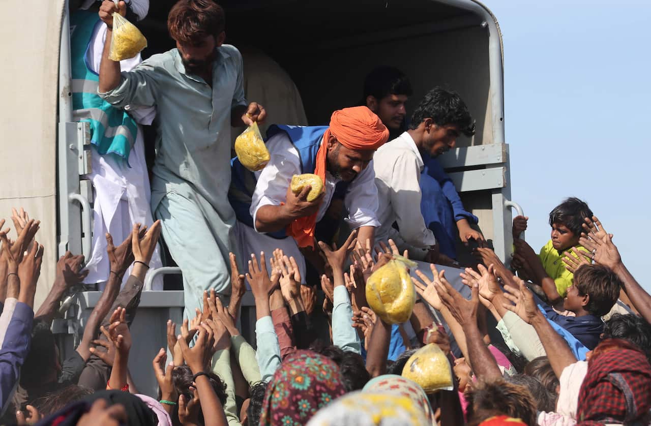 People affected by floods receive aid in Sehwan, Sindh province, Pakistan, 01 September 2022.