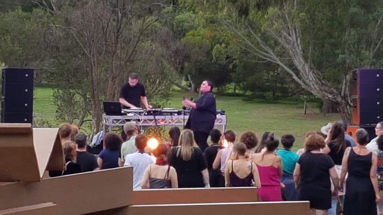 A small group of people watching a musical performance outside