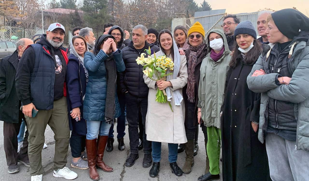 Group of people take photo with woman holding flowers. 