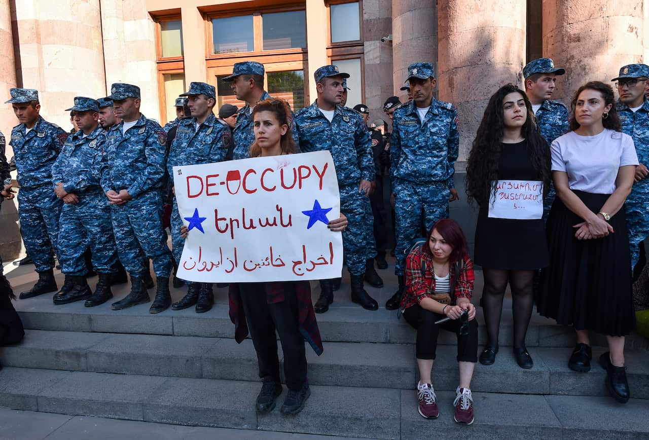 A woman seen outside a government building holding up a white sign.