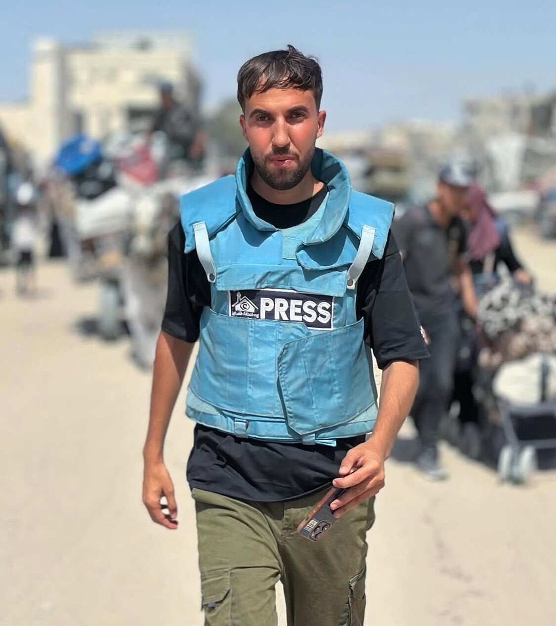 A man in a blue press vest is walking.