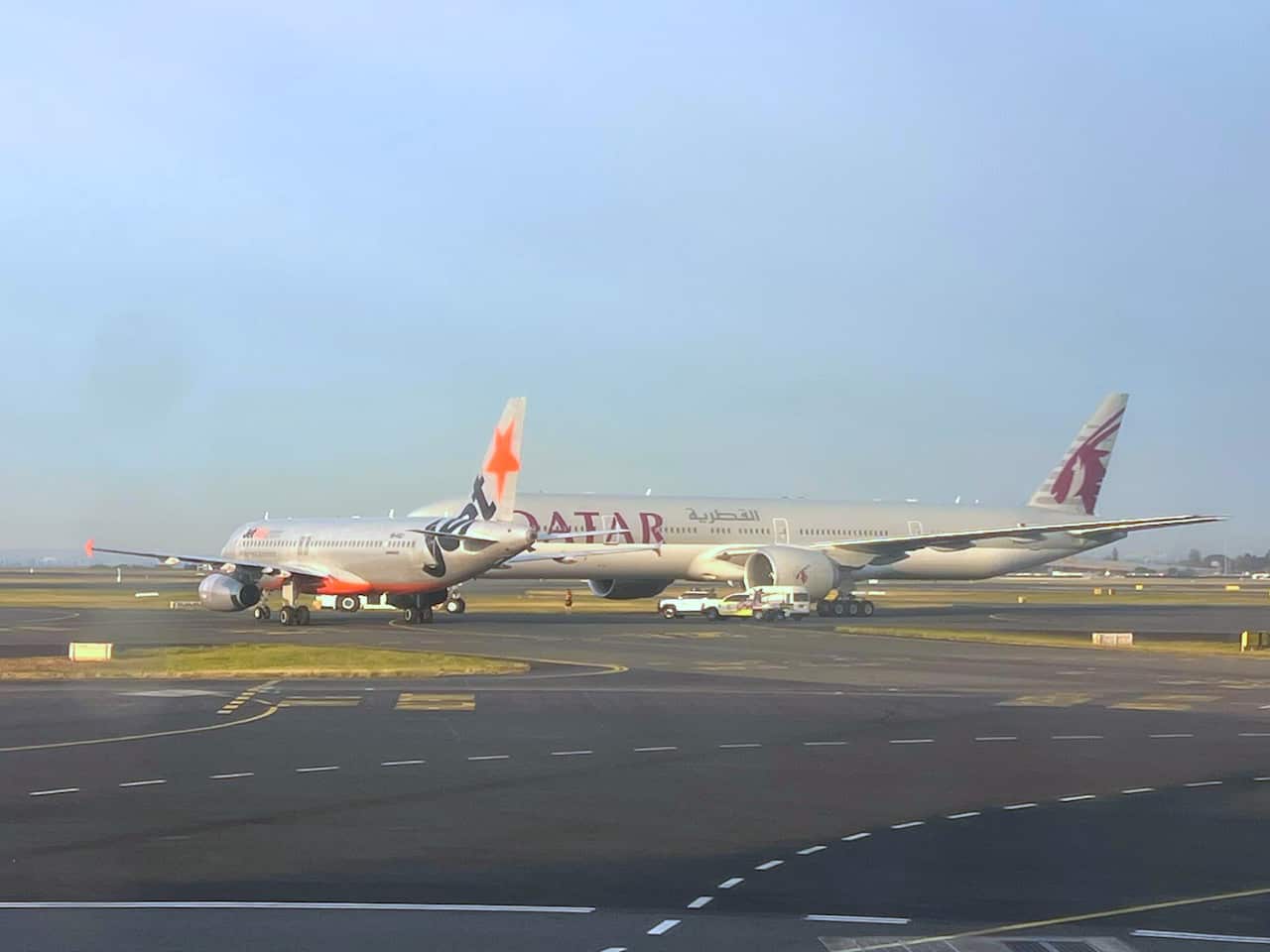Two planes sit very close together on an airport runway.