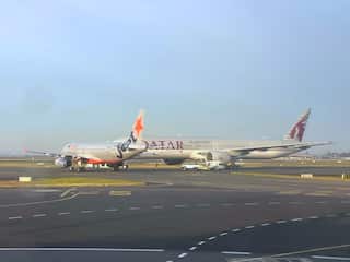 Two planes sit very close together on an airport runway.