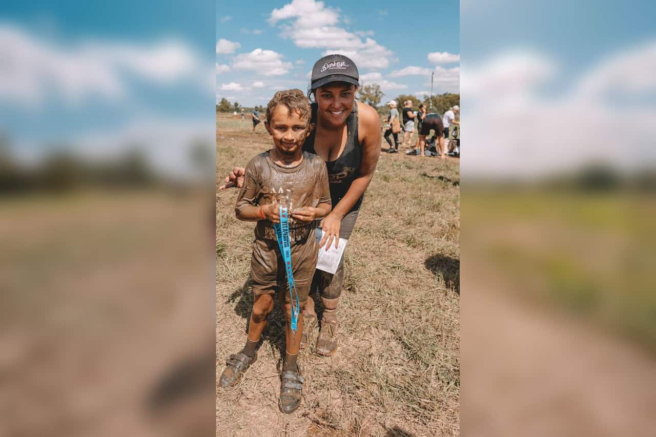 A woman is seen smiling with her child at a tough mudders event.