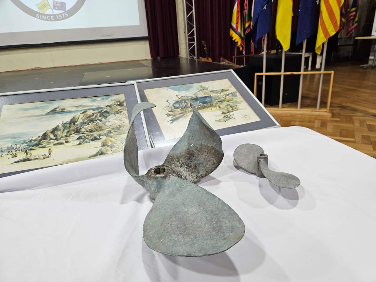 Hai cánh quạt chân vịt của một chiếc thuyền tị nạn và hai bức tranh do một người tị nạn vẽ trong thời gian ở đảo (SBS)