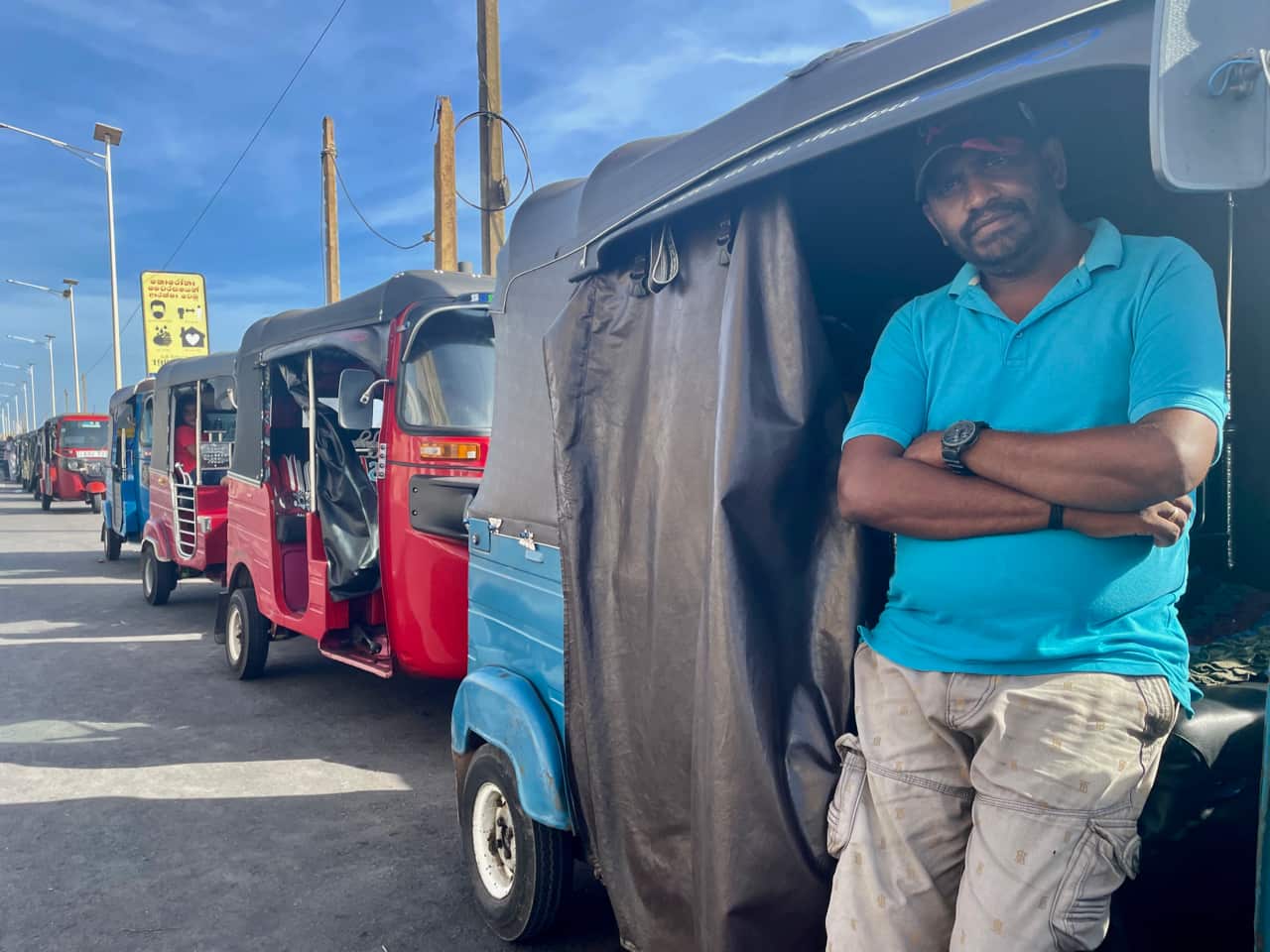 A driver standing in front of his taxi in Colombo, with a line of taxis behind him, as far as the eye can see