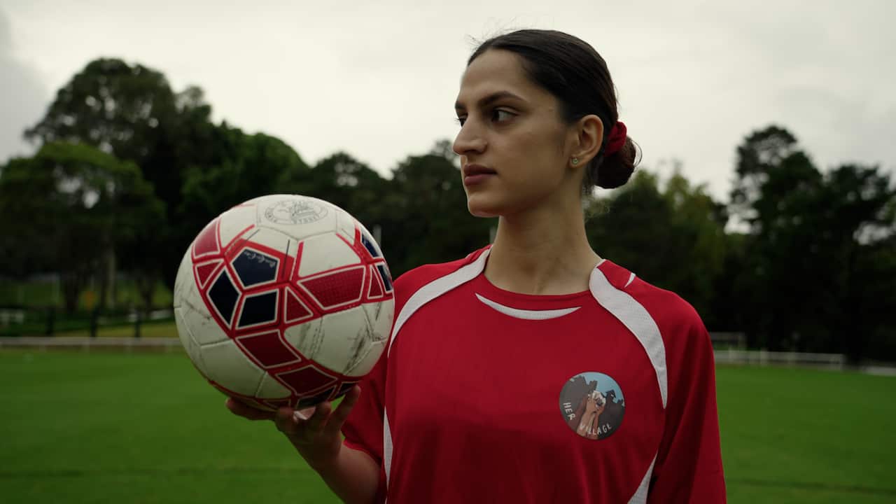 Farhat poses with a football in her hand. 