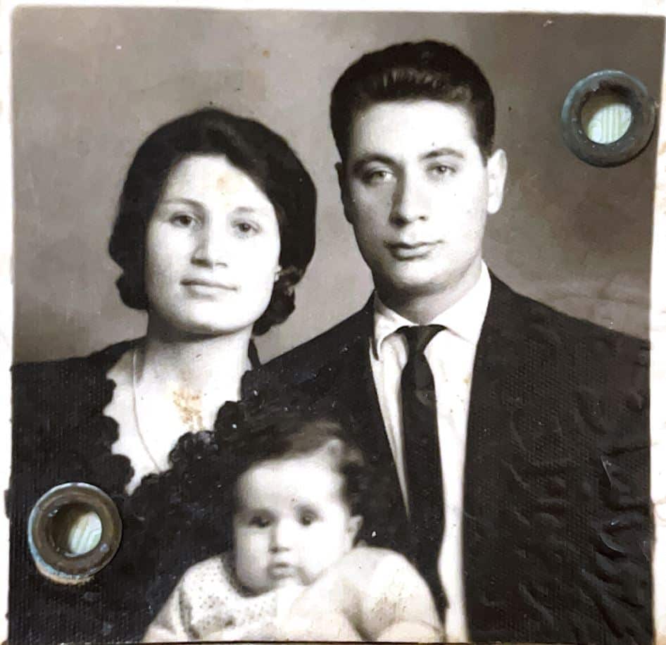 A black and white family photo of a couple and a young girl.