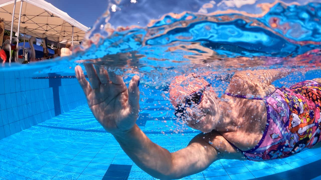 A woman waves underwater. 