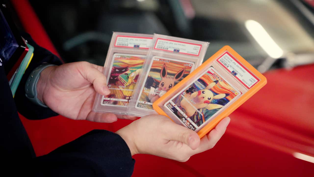 Hands holding Pokémon cards in plastic cases