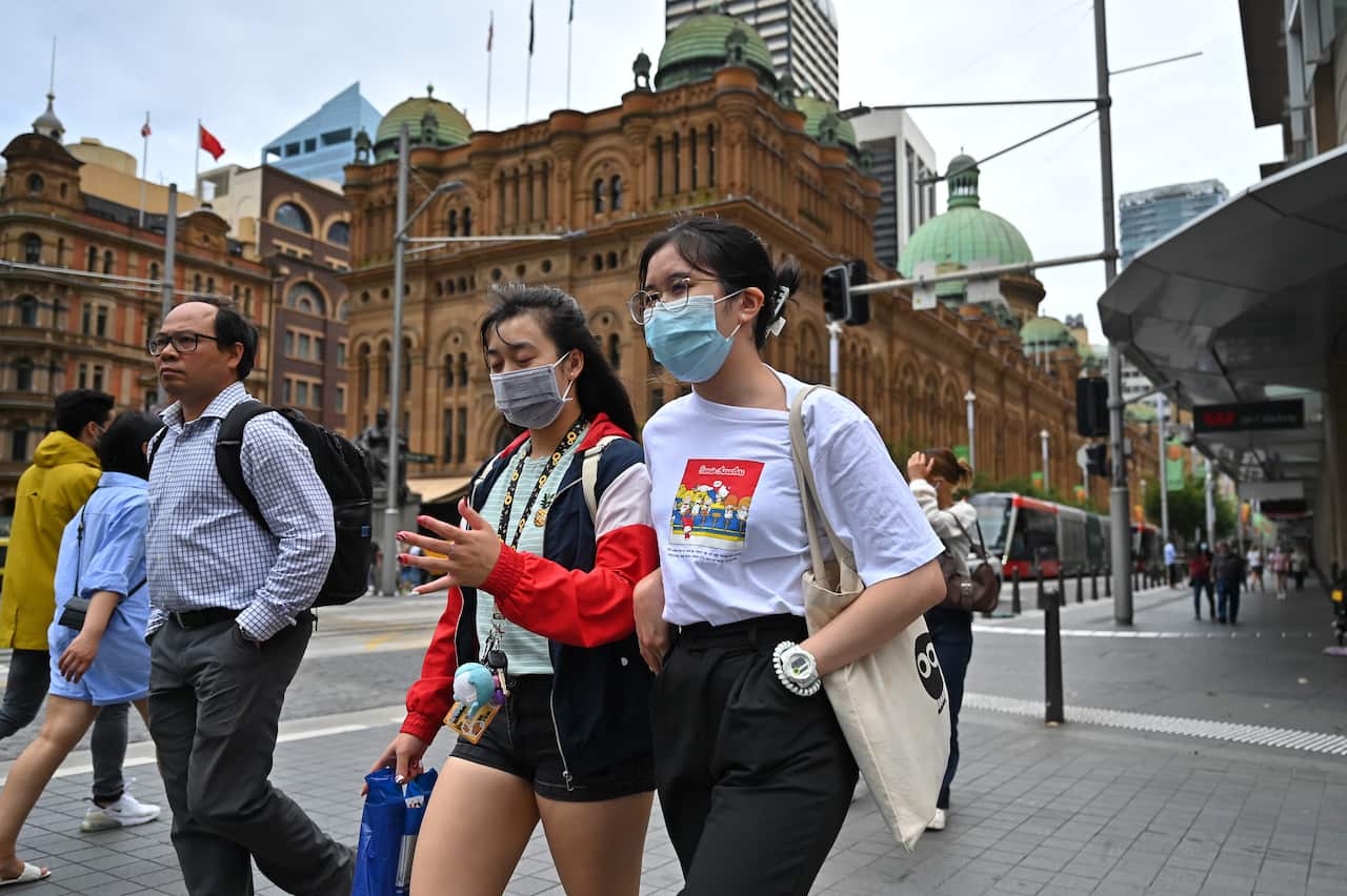 People walk along George Street in Sydney wearing masks.