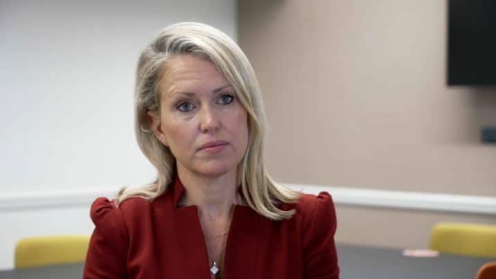 A woman with blonde hair wearing a maroon top.