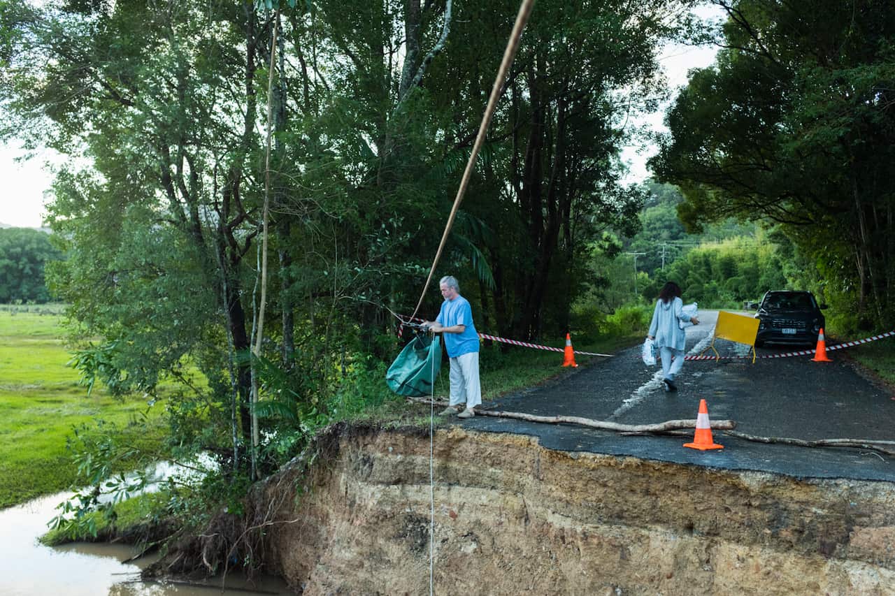 Residents in the Northern Rivers region of NSW aid in the clean-up efforts and examine significant road damage.