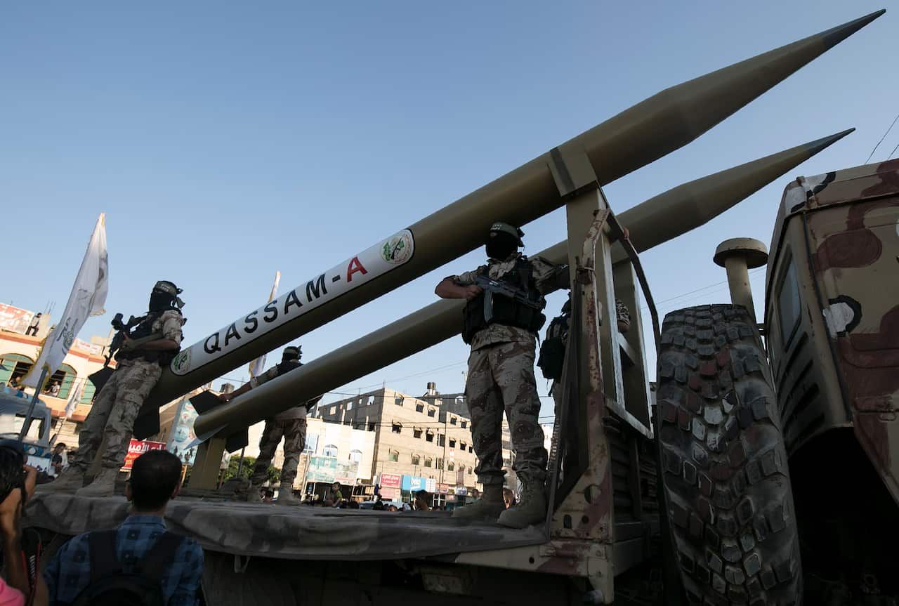 Four members of Hamas stand next to a missile on a truck