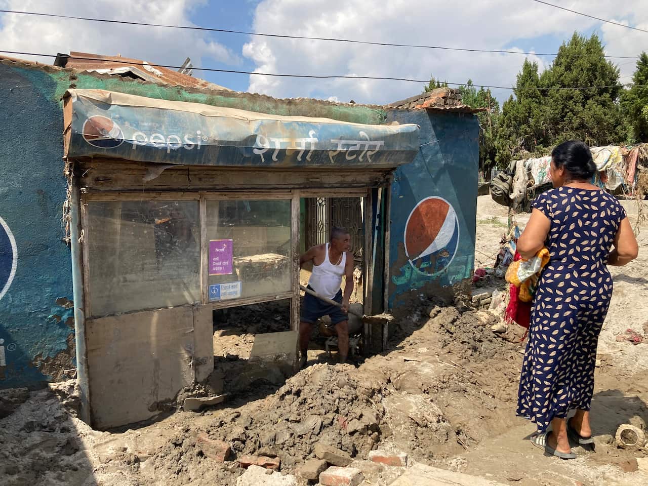 A man cleaning his shop after the floods in Balkhu, Kathmandu.