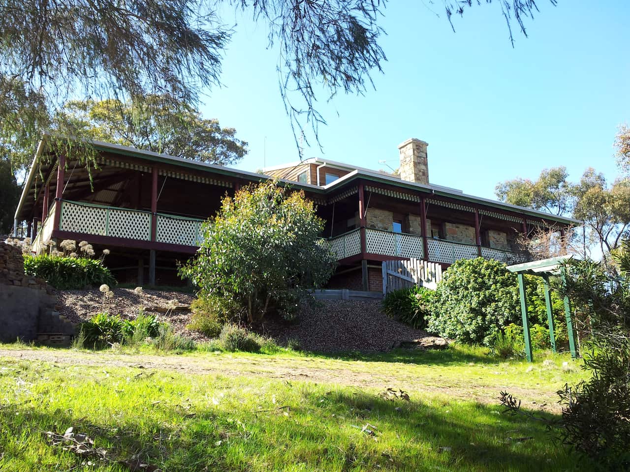 A house with a large veranda on top of a hill.