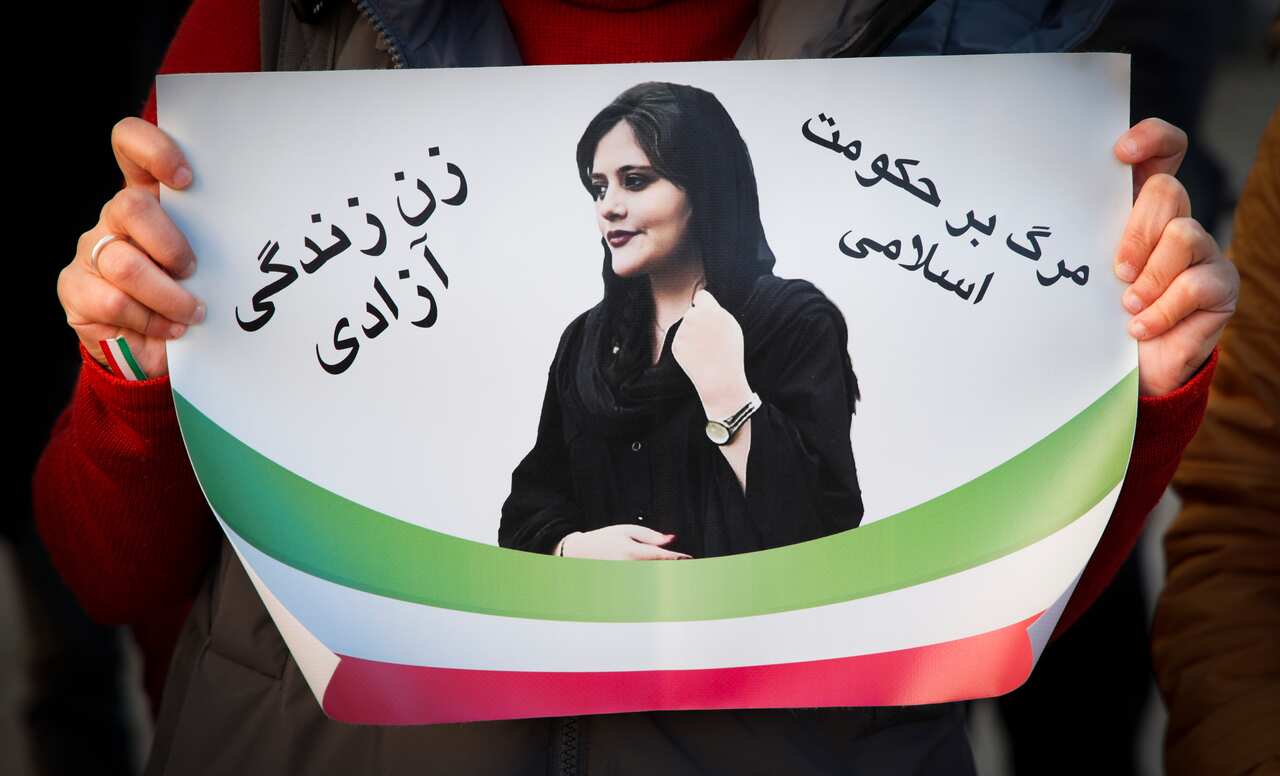 A protester holds a sign with a photo of Mahsa Amini 