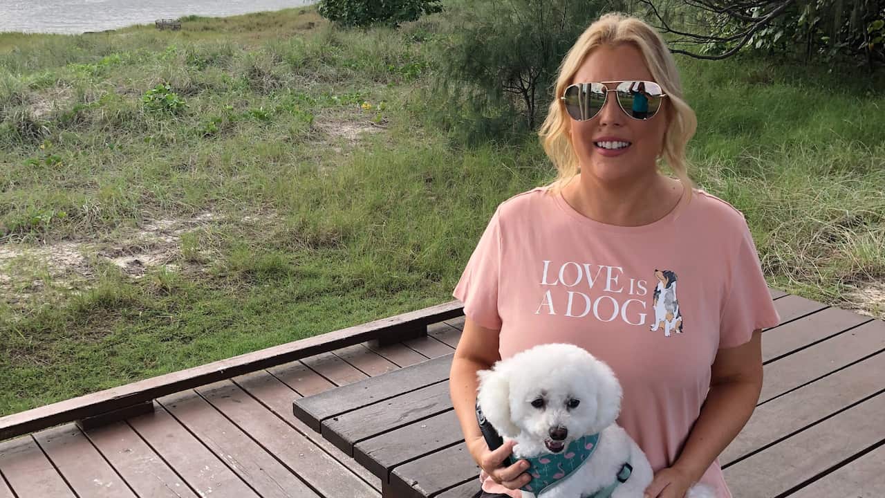 Mel Greig sitting with her dog in her lap.