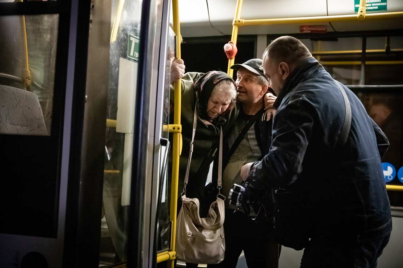 Volunteers assist an old lady to get off the bus 