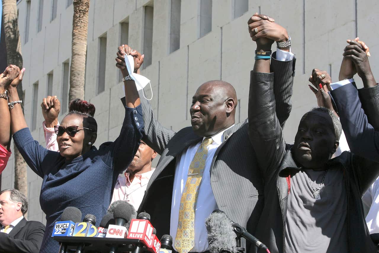 Lawyer Benjamin Crump holds up the arms of Ahmaud Arbery's parents, Wanda Cooper-Jones and Marcus Arbery outside the federal courthouse in Brunswick, Georgia.