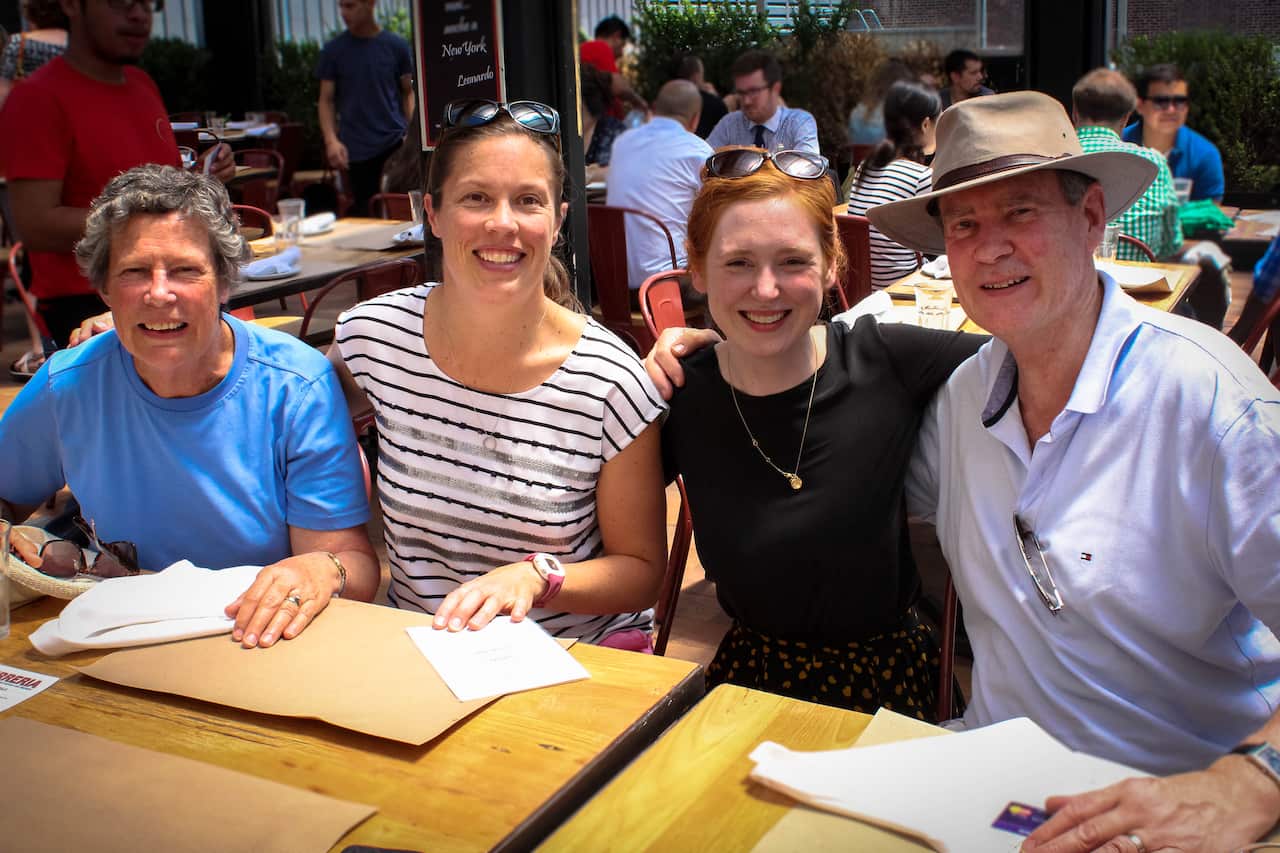 Some members of a family smiling at a restaurant table together.