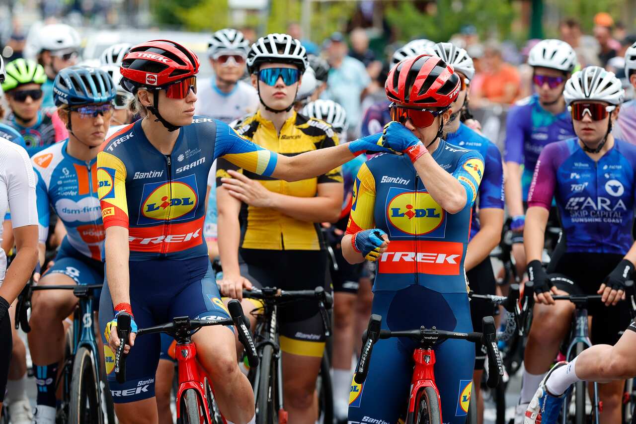 A group of women cyclists watch on as one in the front consoles another.