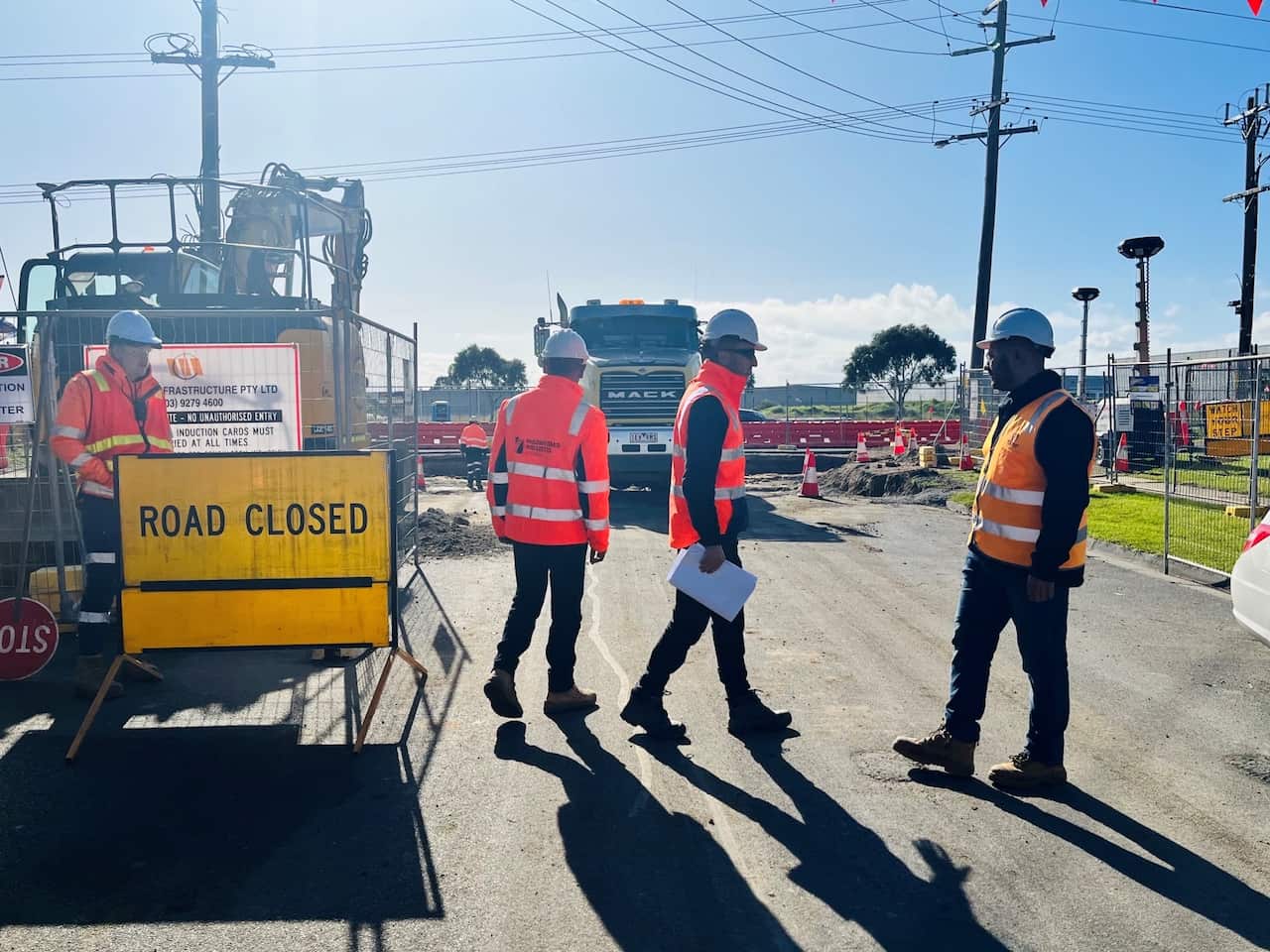 Four men in hi-vis safety gear and hard hats on a road works site