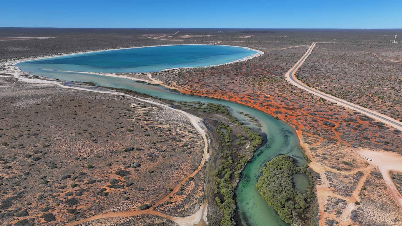 An aerial view of a lagoon of light blue water amid an arid landscape