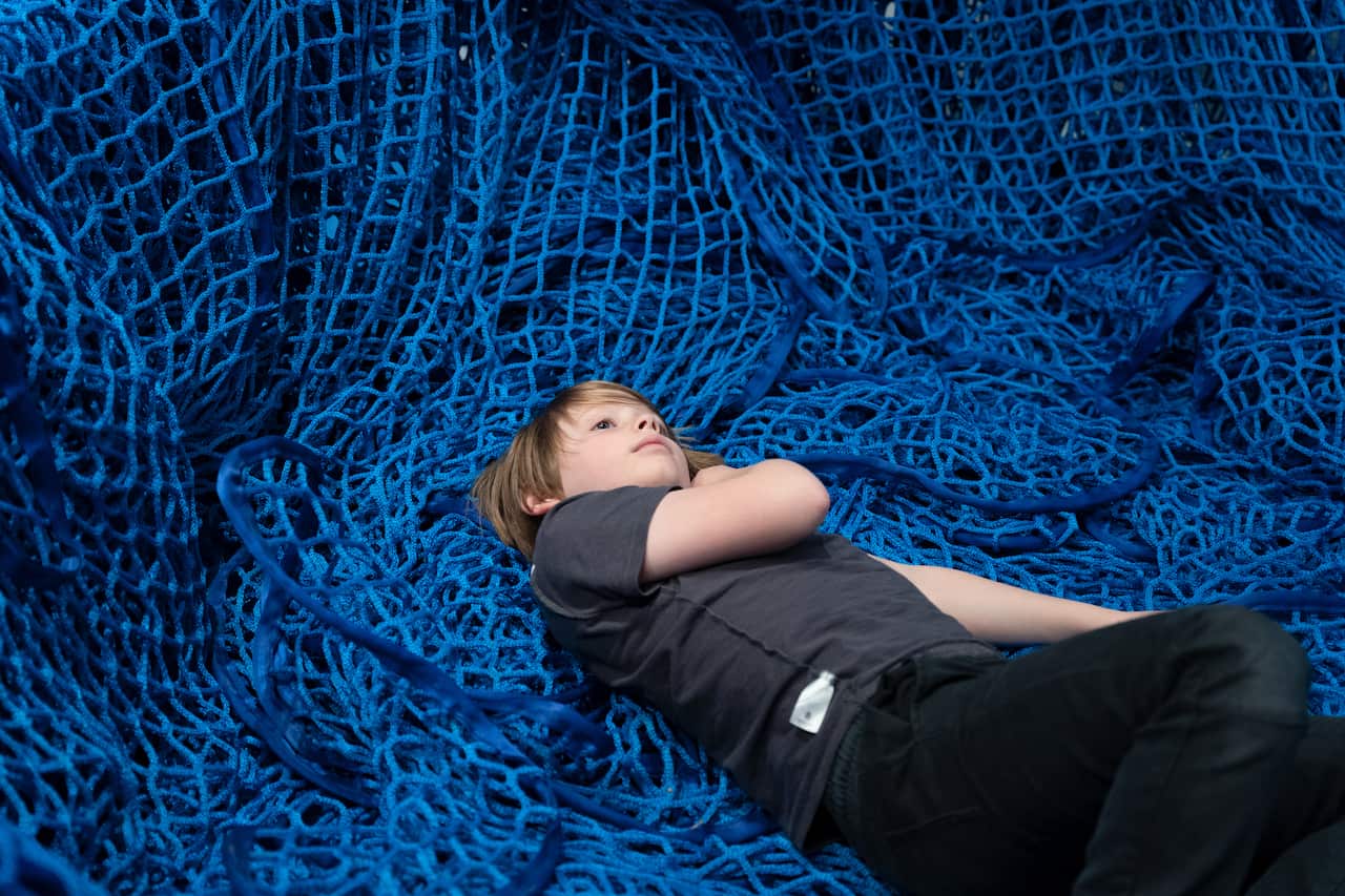 A boy lies down on several blue nets
