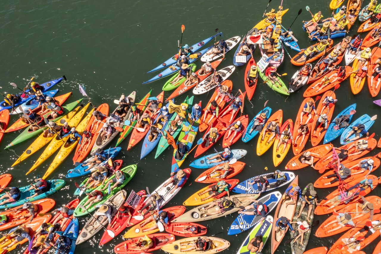 An aerial shot of dozens of people in coloured kayaks