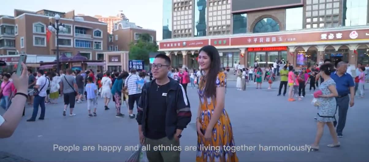 A man and a woman posing for a picture in a busy square in China.