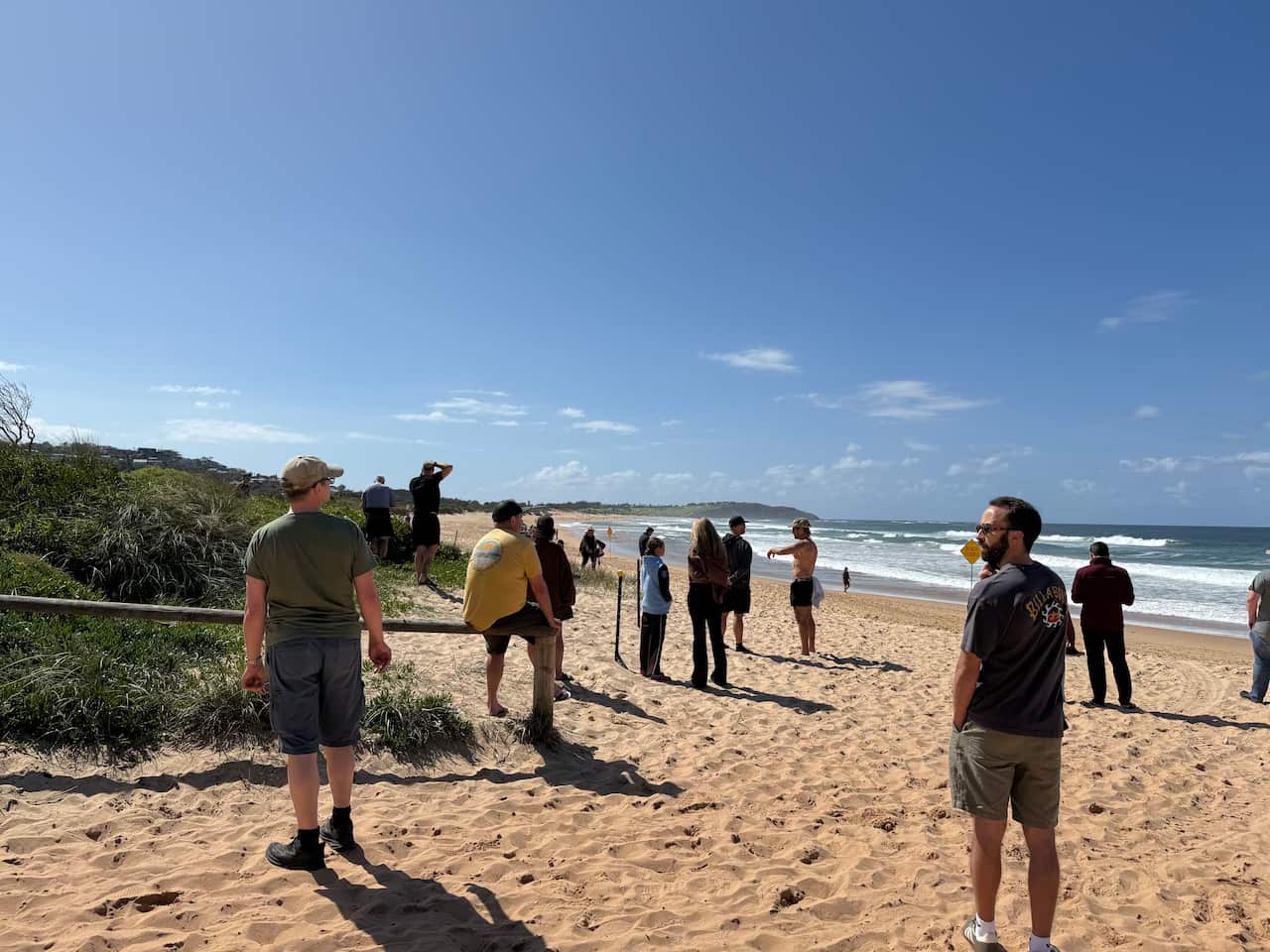 People standing on sand, blue sky behind.