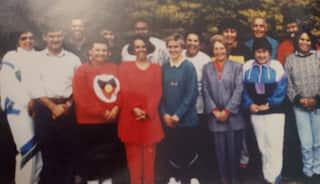 A low-res photograph of a number of young Aboriginal women and men posing together in two rows and smiling.