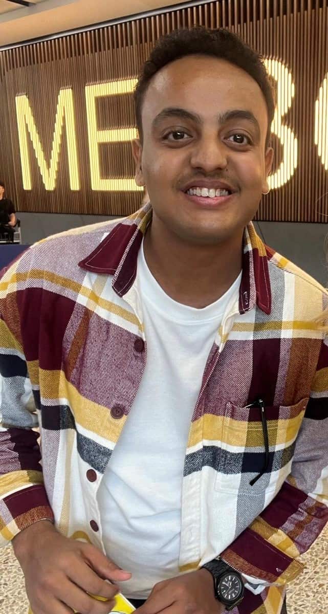 A smiling young man at the 'arrivals' area of Melbourne airport.