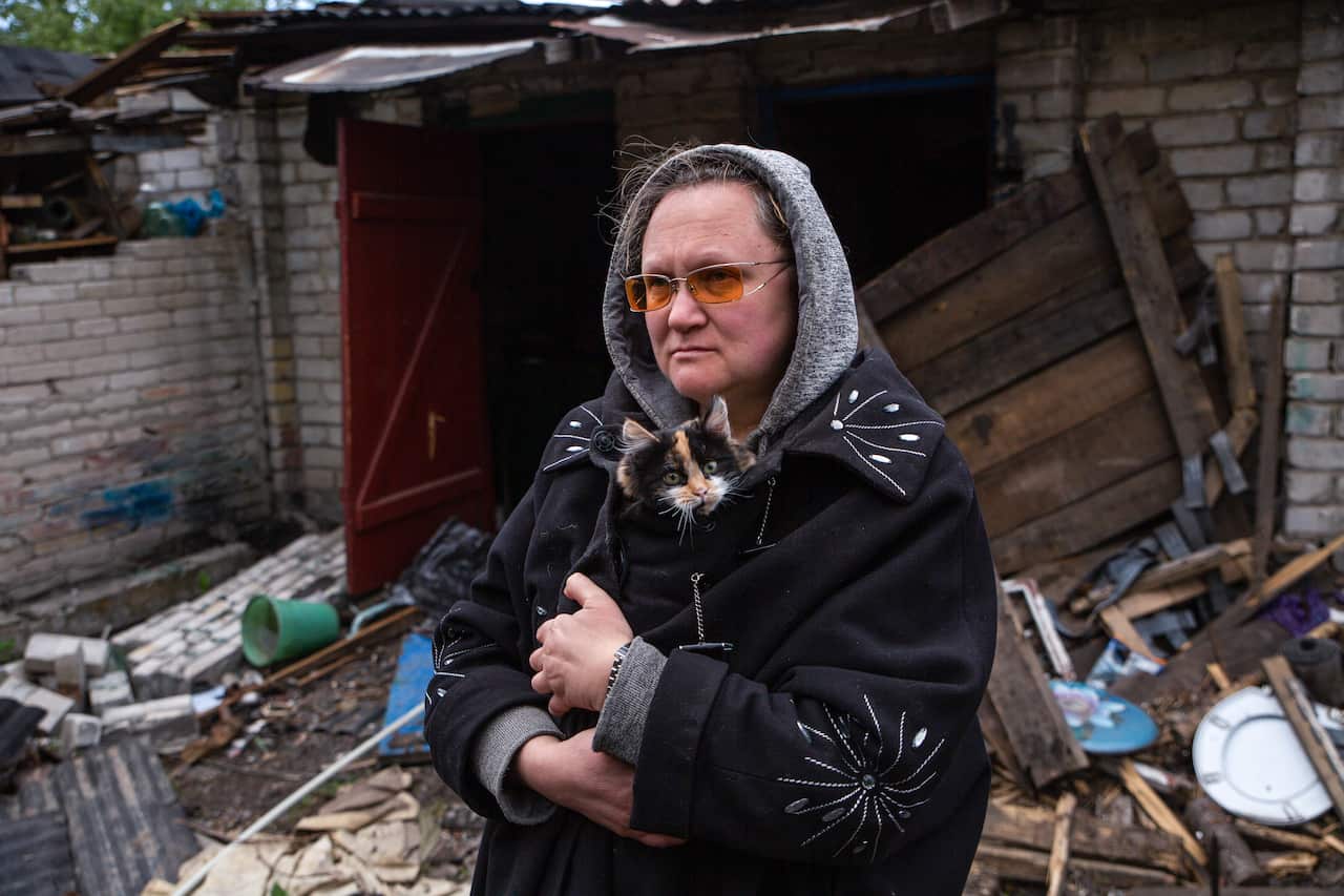 A woman stands outside a destroyed residential building in the town of Popasnaya.