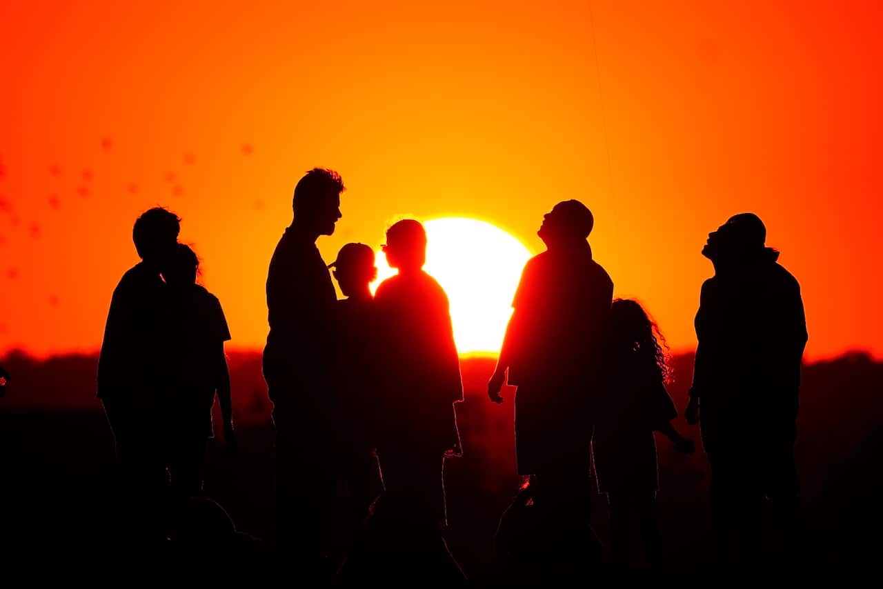 Silhouettes of a group of people in the sunset.