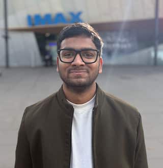 A man wearing glasses smiles while posing for a photo outside Melbourne's IMAX theatre.