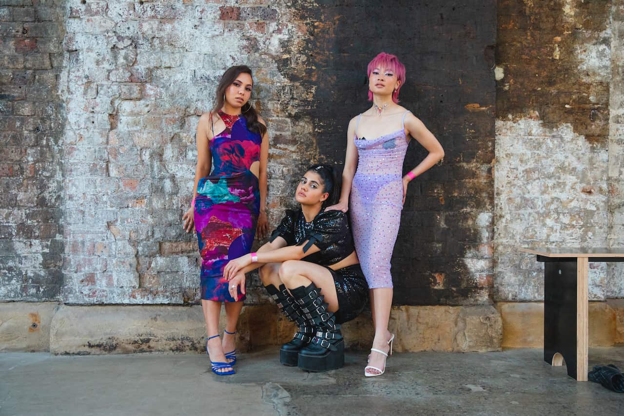 Two women standing either side of another woman who is squatting down