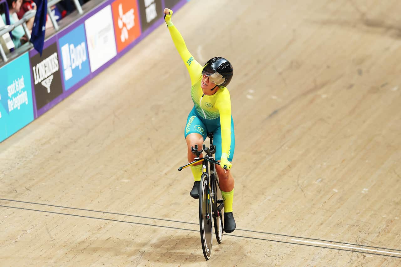 A cyclist in yellow on an indoor track.