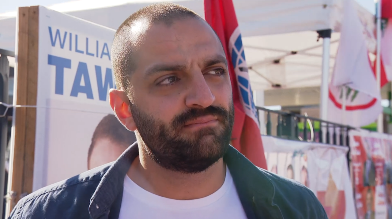 A man looks away with a serious facial expression.
