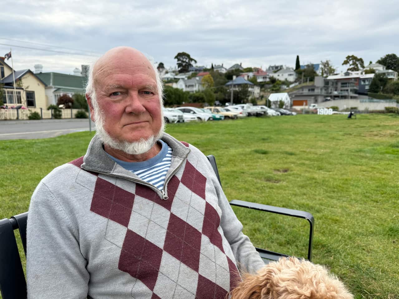 An older man sitting on a bench in a park.